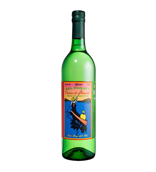 Del Maguey Crema Mezcal 75cl clear glass bottle on white background, pale golden spirit with colorful illustrated label featuring village scene